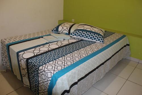 a bed with blue and white sheets and pillows at Villa Hausseman in Rivière-Pilote