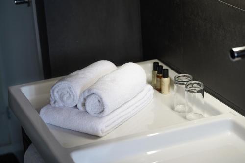 a white bathroom sink with towels on it at Hotel Huis van Bewaring - Bijzonder boutique hotel in historisch pand in Almelo