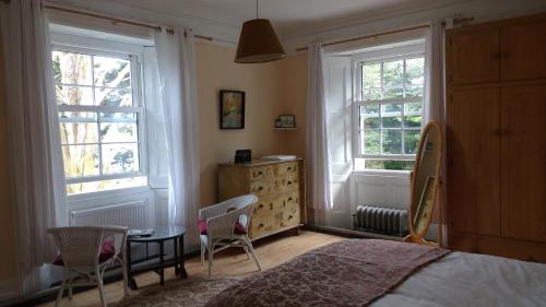 a bedroom with a bed and two chairs and a dresser at Reenglas House in Valentia Island