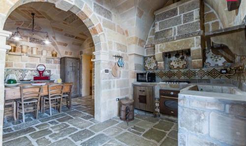 uma cozinha com uma mesa e uma cozinha com uma parede de pedra em Masseria Curice em Corsano