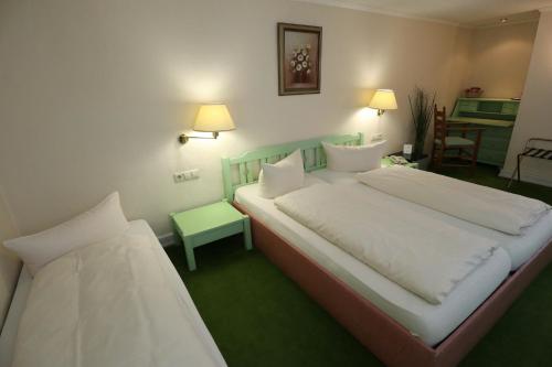 a bedroom with two beds and a green floor at Schwarzwaldhotel Stollen in Gutach im Breisgau