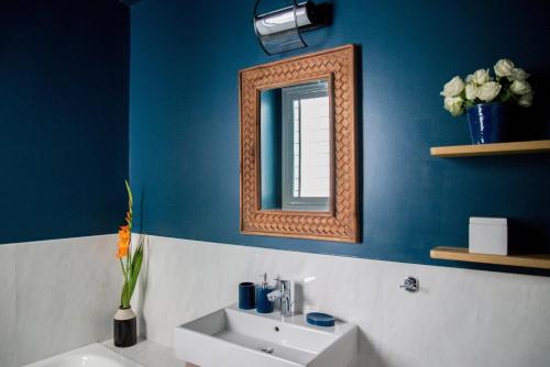a blue bathroom with a sink and a mirror at Virtue by Stylish Stays in Athens