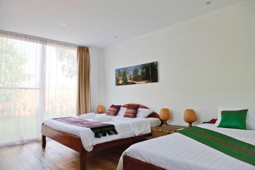 a bedroom with two beds and a window at Angkor Private villa Siem Reap in Siem Reap