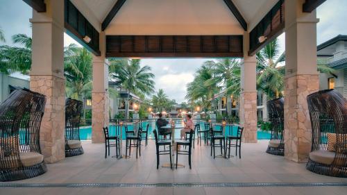 un patio con mesa y sillas frente a la piscina en Luxury Apartments at Temple Resort and Spa Port Douglas, en Port Douglas