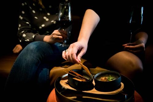 a woman eating food in a bowl with a glass of wine at Fitz Roy Urban Hotel, Bar and Garden in Maastricht