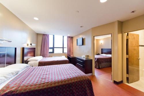 a hotel room with two beds and a mirror at Dynasty Hotel and Suites New York LaGuardia Hotel in Queens