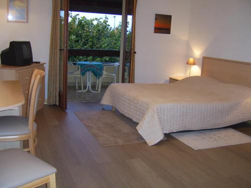 une chambre avec un lit et un balcon avec une table dans l'établissement Hôtel Les Pavillons du Golf, à Évian-les-Bains