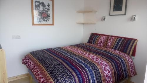 een bed met een kleurrijke deken erop bij Otter Bothy in Uig