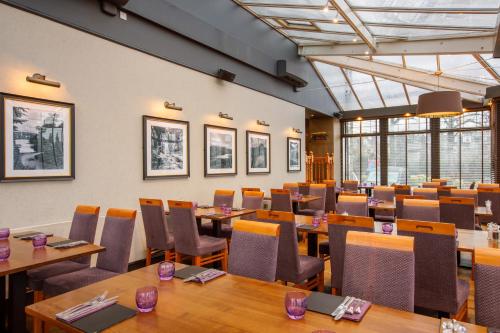 a dining room with tables and chairs and windows at Ferryhill House Hotel in Aberdeen