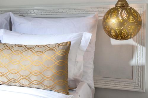 a bed with white pillows and a gold chandelier at Marrakech Ryads Parc All inclusive in Marrakech