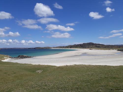 a beach with sand and water and mountains in the background at Otter Bothy in Uig