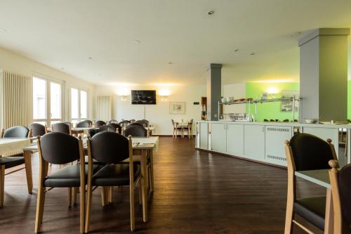 ein Restaurant mit Tischen und Stühlen und eine Küche in der Unterkunft Hotel am Schillerplatz in Pleidelsheim