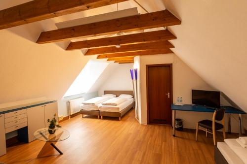 ein Schlafzimmer mit einem Bett und einem Schreibtisch im Dachgeschoss in der Unterkunft Hotel am Schillerplatz in Pleidelsheim