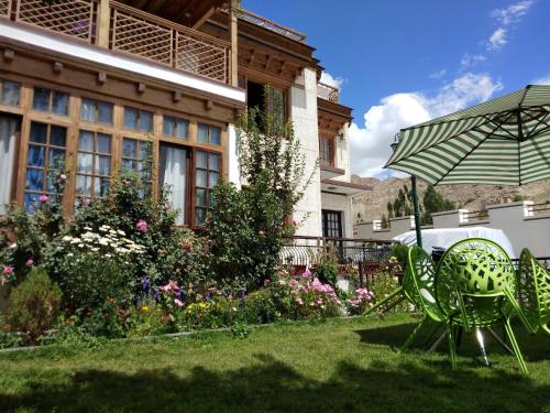 a garden with two chairs and an umbrella in front of a house at New Royal Guest House in Leh