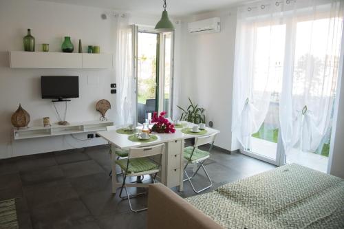 a white dining room with a table and a tv at La Strelitzia Cervo Mare in Cervo