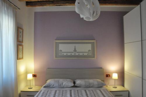 a bedroom with a bed and two lamps and a wall at Casa della Magnolia in Conegliano