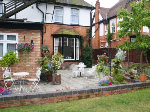 a patio with chairs and tables in front of a house at Elmdon Lodge in Birmingham
