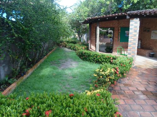a garden with flowers and a brick house at Pousada do Riacho in Barreirinhas
