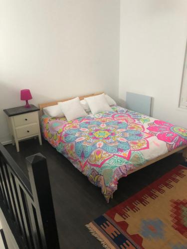 ヴィルパントにあるJOLIE PETITE MAISONのベッドルームにカラフルな掛け布団付きのベッド1台