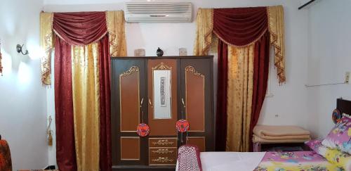 a bedroom with curtains and a bed and a cabinet at Nuba Dool in Aswan