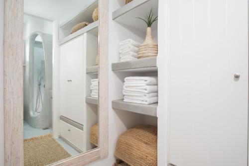 a mirror in a bathroom with towels on shelves at Perla Suites - Delmar Collection in Pollonia
