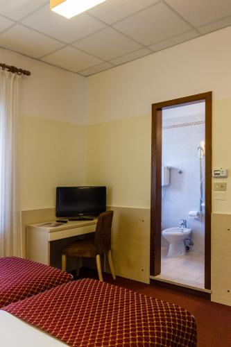 a bedroom with a desk and a bathroom with a toilet at Hotel Sant'Ilario in Rovereto