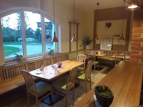 a restaurant with wooden tables and chairs and a large window at Simandlhof in Hitzendorf