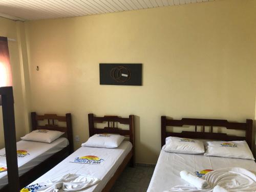a room with three beds in it with a wall at Hotel Ondas do Mar in Salinópolis