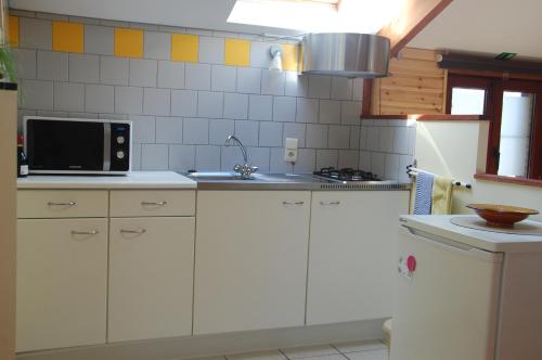 een keuken met witte kasten en een magnetron bij Vakantiestudio 'Kleine Johannes' in Duffel