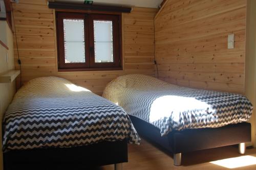 twee bedden in een kamer met houten wanden bij Vakantiestudio 'Kleine Johannes' in Duffel
