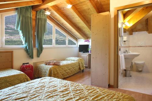 a bedroom with two beds and a bathroom with a sink at Hotel Sant'Ilario in Rovereto