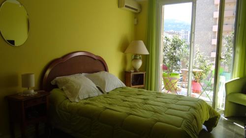 - une chambre verte avec un lit et une fenêtre dans l'établissement Chambre Ajaccio, à Ajaccio