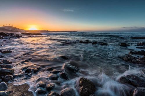 a sunset on a beach with rocks at Casa Avenida del Agujero in Gáldar