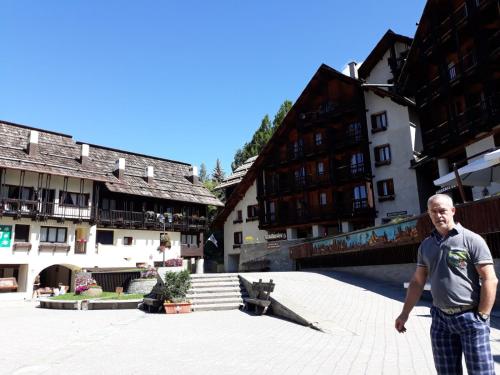 a man standing in the middle of a courtyard with buildings at Jackson in Sauze di Cesana