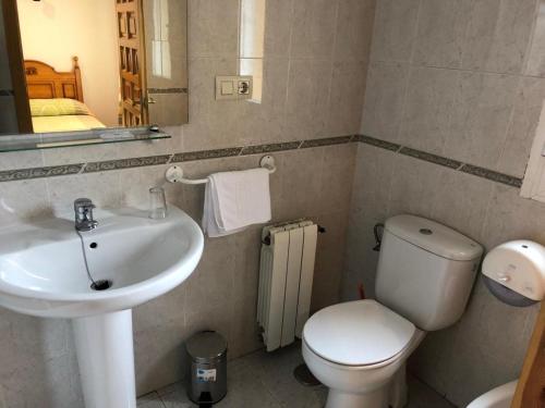 a bathroom with a sink and a toilet and a mirror at Hostal Arias in Zafra