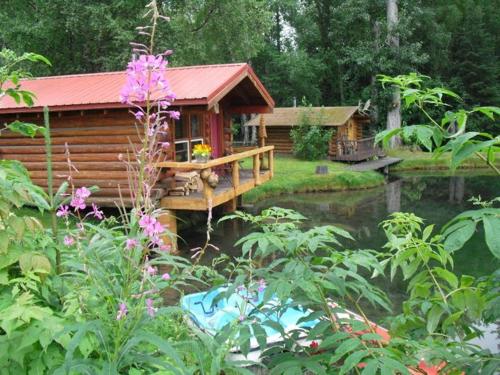 a log cabin with a bridge over a pond at Hope Alaska's Bear Creek Lodge in Hope