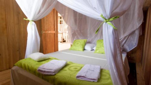 a bedroom with a bed with a canopy and towels at La Ceiba, Amazonas in Leticia