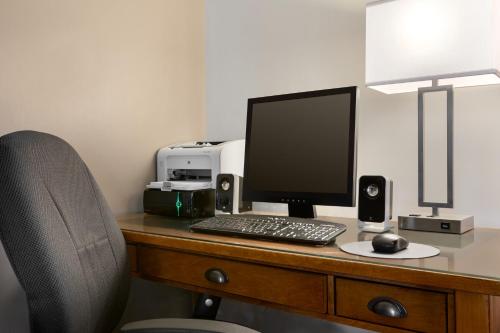 a desk with a computer monitor and a keyboard and mouse at Travelodge Suites by Wyndham New Glasgow in New Glasgow