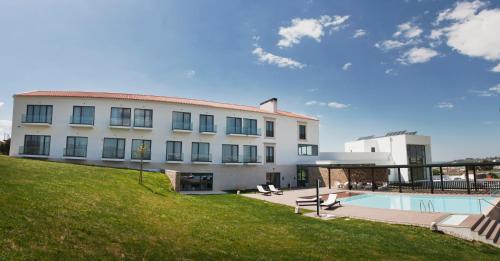 a large white building with a swimming pool and a yard at Real Abadia, Congress & Spa Hotel in Alcobaça