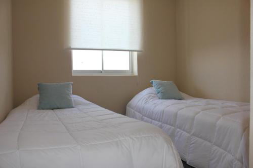 two white beds in a room with a window at Resort Laguna Bahía, Océano Piso 12 Algarrobo in Algarrobo