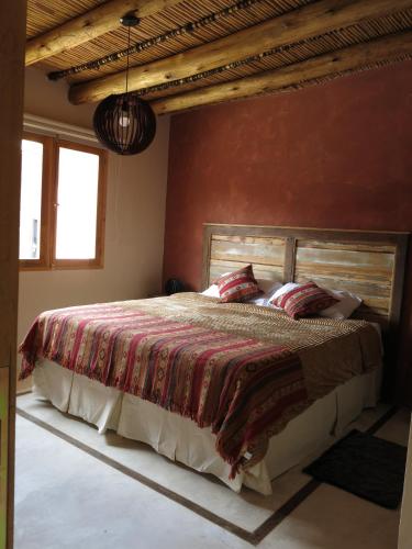 a bedroom with a large bed with a red wall at Casatilcara Cabañas in Tilcara