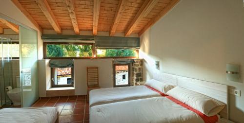 a living room with two beds and a window at Hotel Rural Las Encinas in Santa María de Redondo