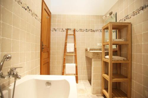 a bathroom with a tub and a toilet and a shelf at Clos des Oliviers in Lumio