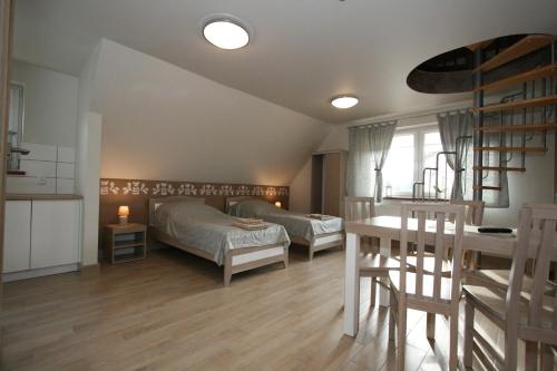 a bedroom with two beds and a table and a kitchen at Noclegi Cameleon in Słupca