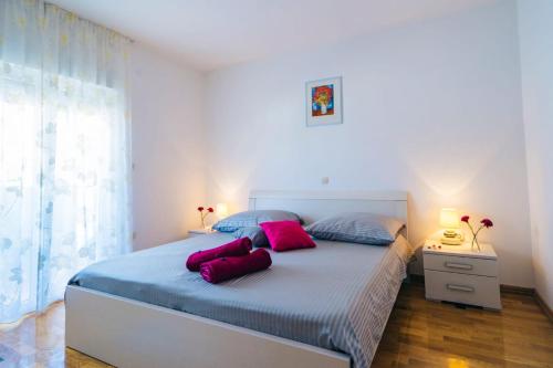 een slaapkamer met een bed met roze kussens erop bij Apartmani Lucante in Split