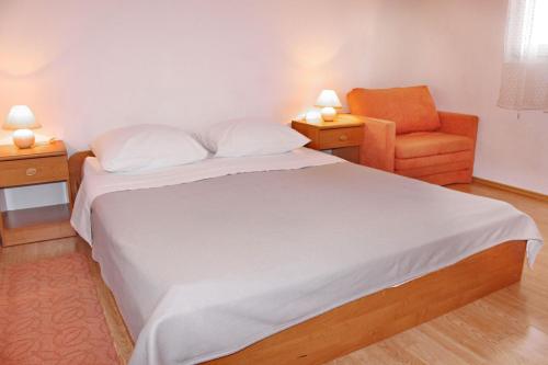 - une chambre avec un lit et une chaise orange dans l'établissement Apartments Remi - 300m from sea, à Nin