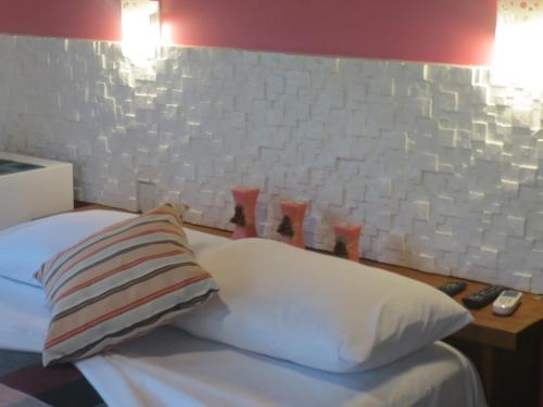 a bedroom with a bed with a pillow and a wall at Pousada Guapuruvu in Abraão
