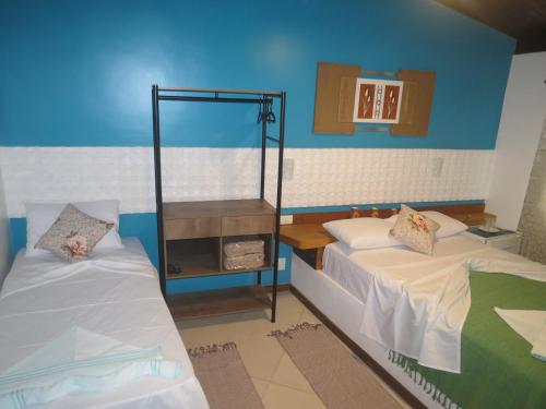 a bedroom with two beds and a blue wall at Pousada Guapuruvu in Abraão