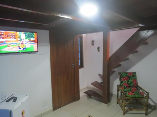 a living room with a tv and a stair case at Pousada Guapuruvu in Abraão