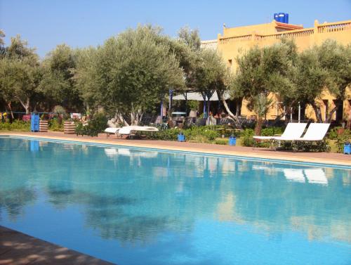 a swimming pool with trees and a building in the background at Atlas Resorts in Aït Ourir